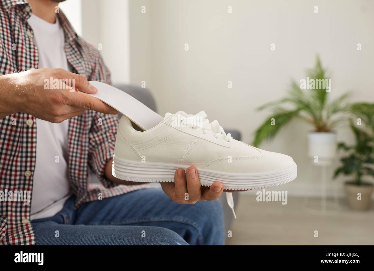 Der Mann setzt neue orthopädische Einlegesohle mit Fußgewölbestütze in einen bequemen orthopädischen Schuh Stockfoto