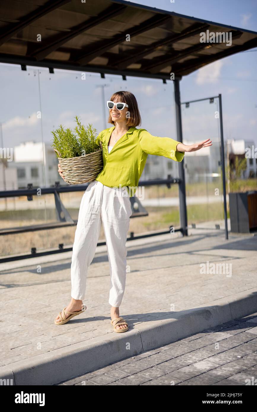 Frau mit Blumentopf an einer Bushaltestelle Stockfoto