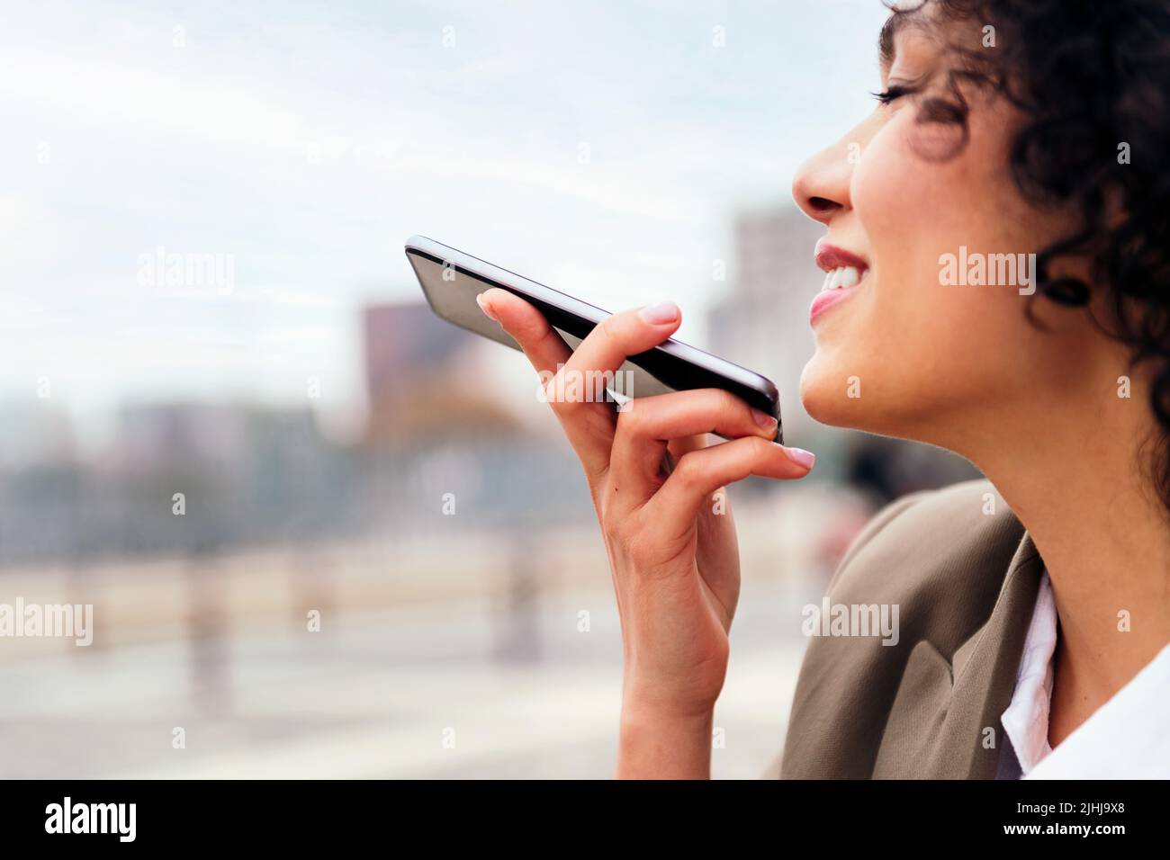 Lächelnde Frau, die eine Nachricht mit einem Handy aufzeichnet Stockfoto