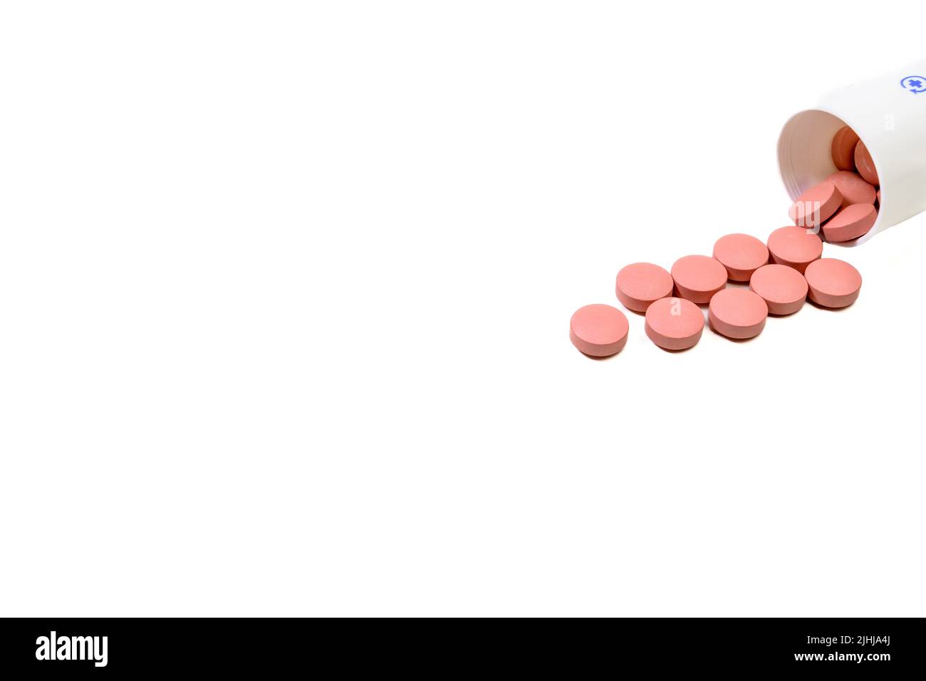 Rosa Medikamentenpillen verschüttet aus einer weißen Flasche auf weißem Hintergrund Stockfoto