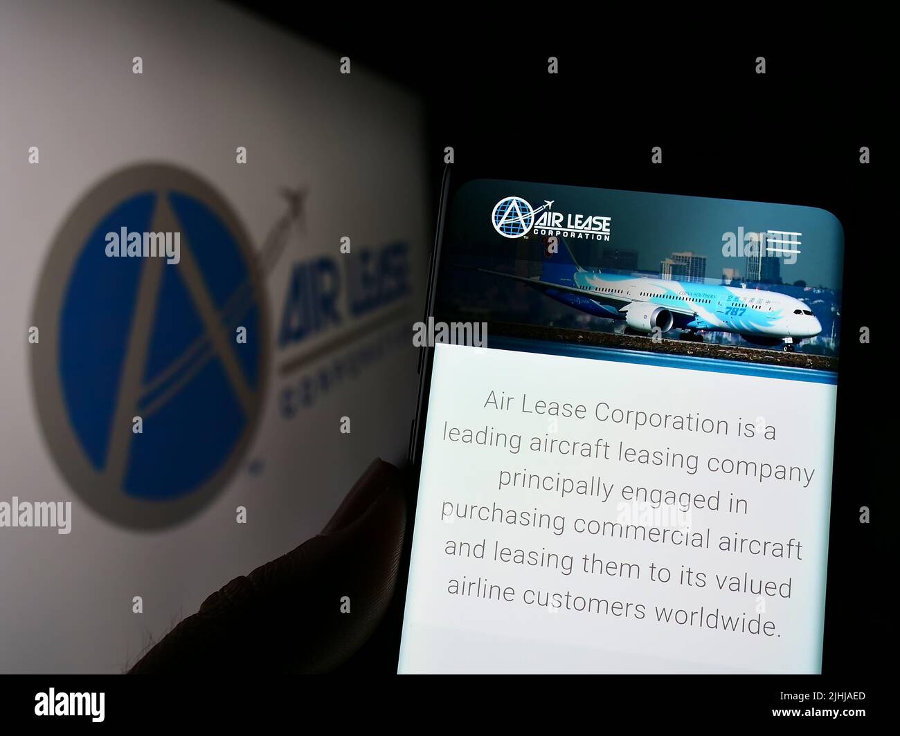 Person mit Mobiltelefon auf der Website der US-Leasinggesellschaft Air Lease Corporation (ALC) auf dem Bildschirm mit Logo. Konzentrieren Sie sich auf die Mitte des Telefondisplays. Stockfoto