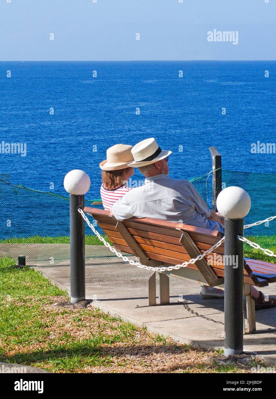 Ältere Paare mit Strohhüten sitzen auf einer Bank und genießen Meerblick, Taurito, Grand Canary, Kanarische Inseln, Spanien, Europa Stockfoto