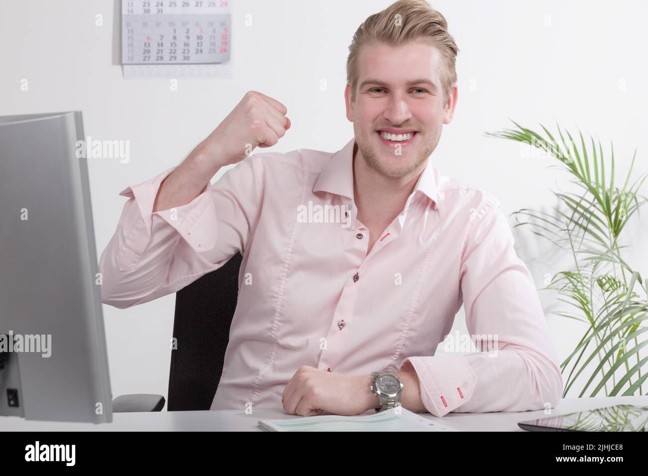 Der Mann hat seine Steuererklärung oder seine Papierarbeit am Schreibtisch gemacht und zeigt eine Siegerpose Stockfoto