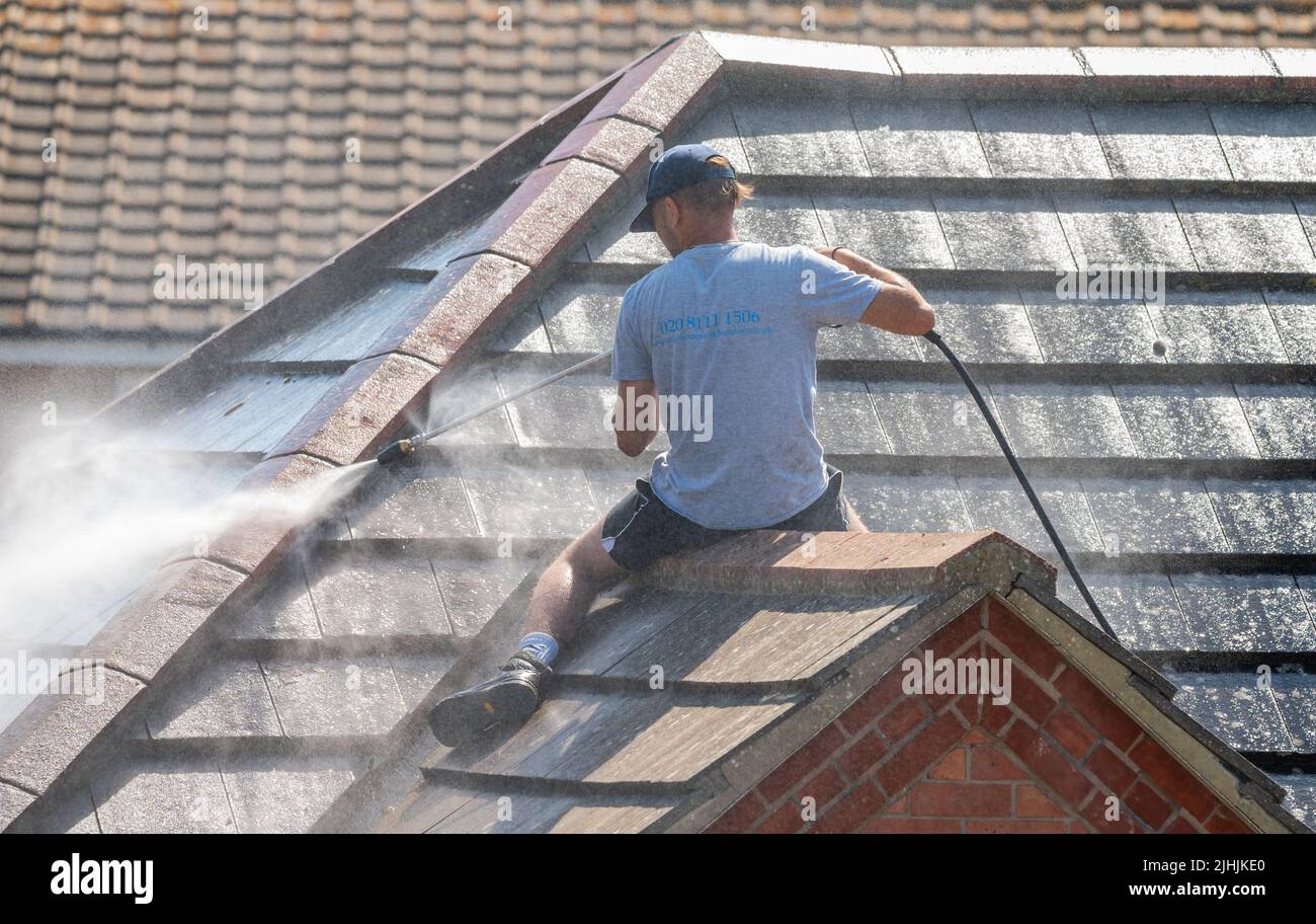 Rustington, West Sussex, Großbritannien. Dienstag, 19.. Juli 2022. Ein Mann reinigt heute Morgen mit einem Jetwash ein Hausdach, während die Hitze in der Nähe der Südküste weiter schmilzt. Kredit: Geoff Smith/Alamy Live Nachrichten Stockfoto