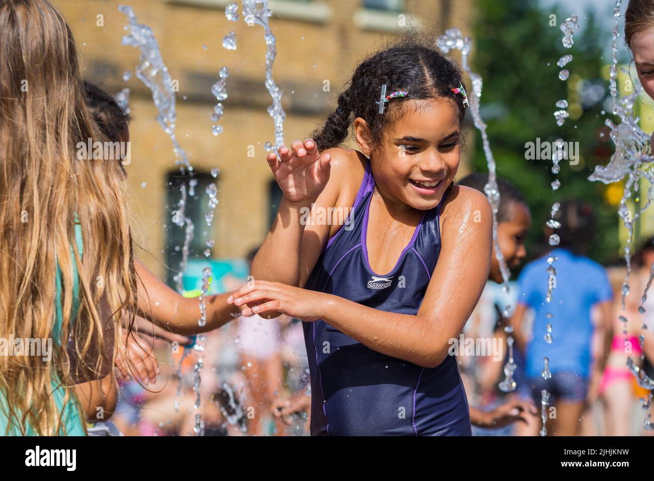 London, Großbritannien - 18. Juli 2022 - Hitzewelle in London, Kinder spielen mit Wasser, um sich an den Brunnen am Granary Square in Kings Cross abzukühlen Stockfoto