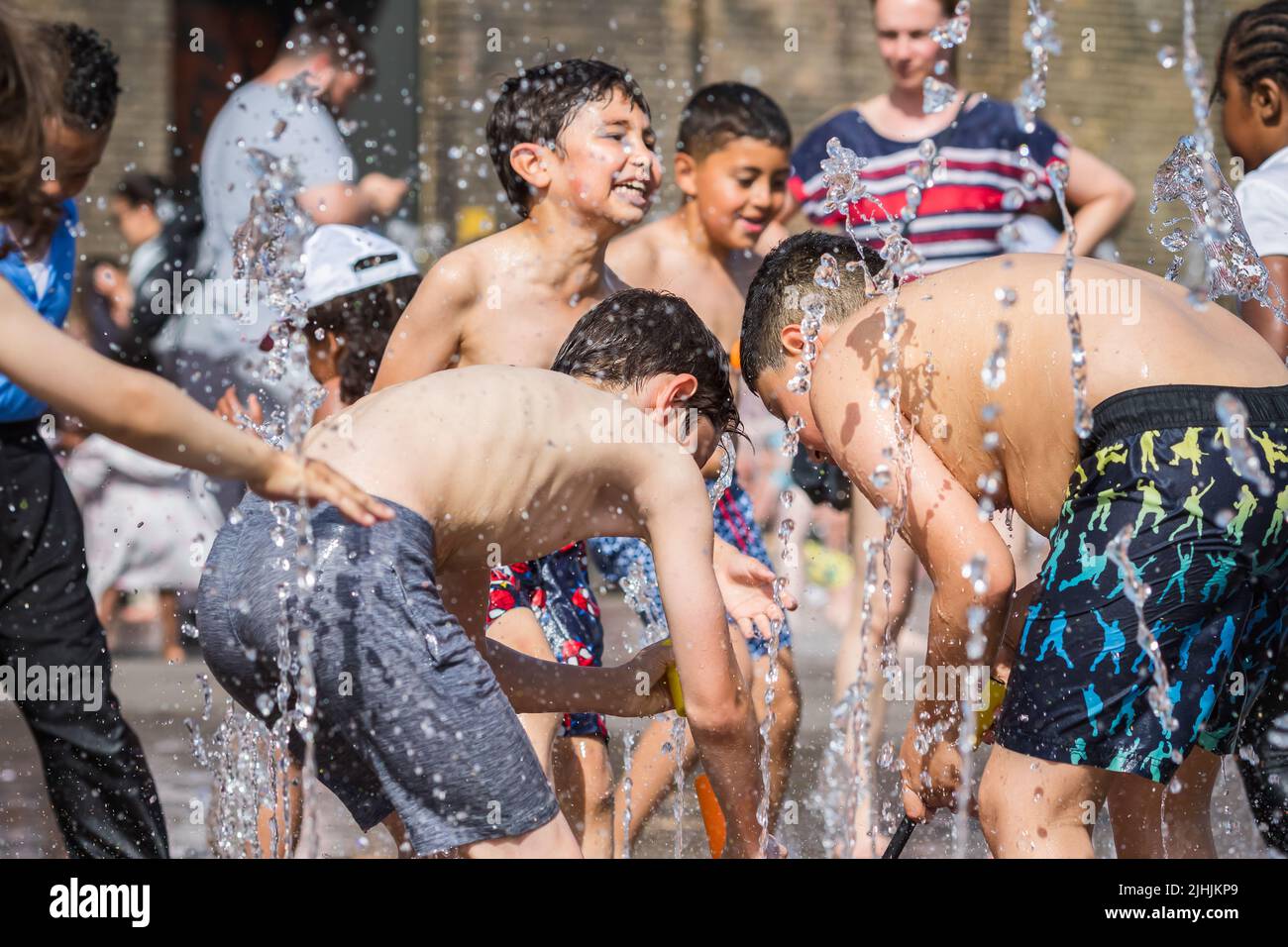 London, Großbritannien - 18. Juli 2022 - Hitzewelle in London, Kinder spielen mit Wasser, um sich an den Brunnen am Granary Square in Kings Cross abzukühlen Stockfoto