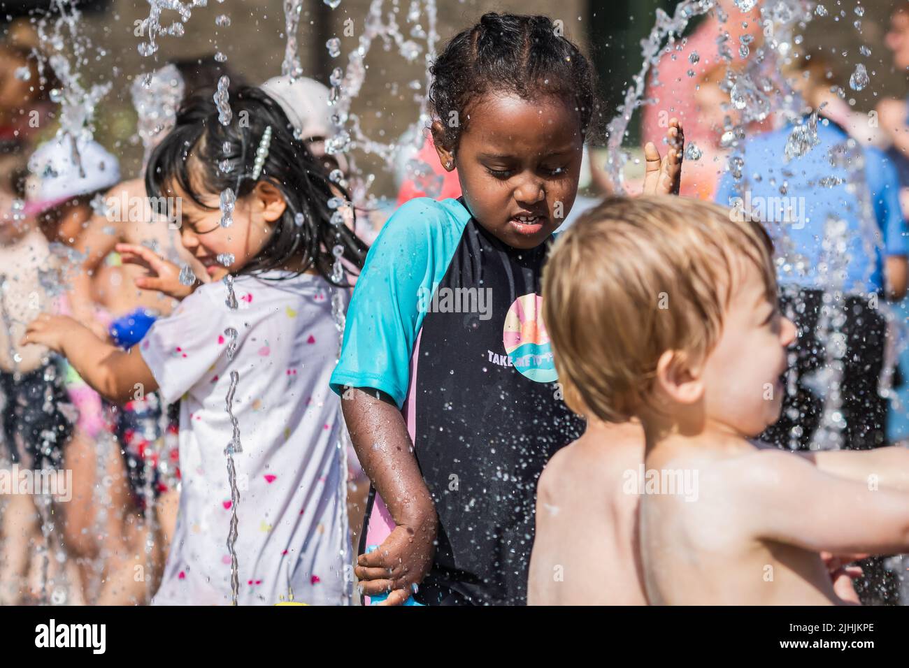 London, Großbritannien - 18. Juli 2022 - Hitzewelle in London, Kinder spielen mit Wasser, um sich an den Brunnen am Granary Square in Kings Cross abzukühlen Stockfoto