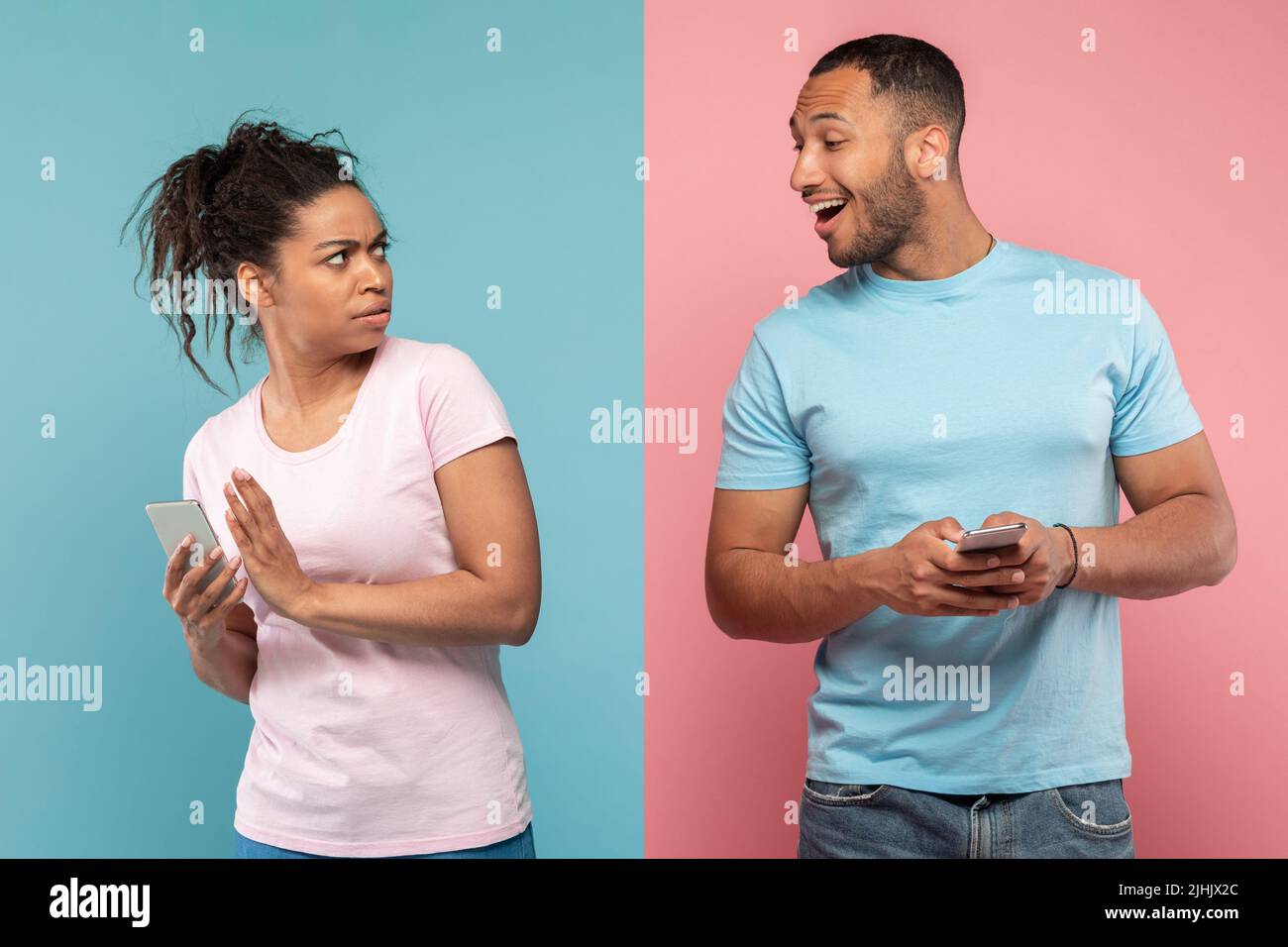 Datenschutzkonzept. afroamerikanischer Mann, der versucht, auf das Handy seiner Freundin zu schauen, und eine Dame, die den Bildschirm ihres Telefons versteckt Stockfoto