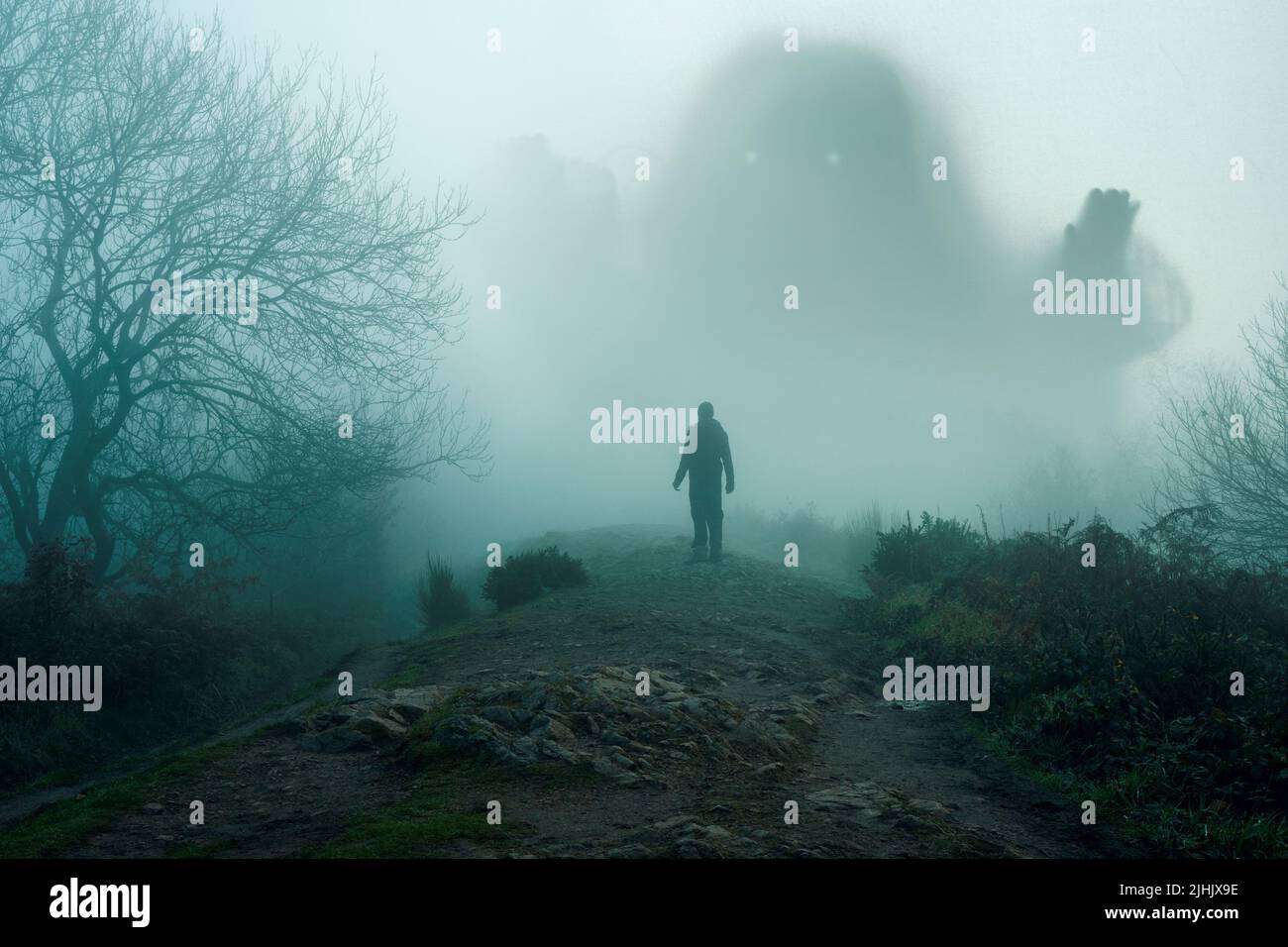 Eine riesige gruselige Entität, die aus dem Nebel auftaucht. Wenn eine Person aufschaut. An einem düsteren Wintertag auf dem Land. Stockfoto