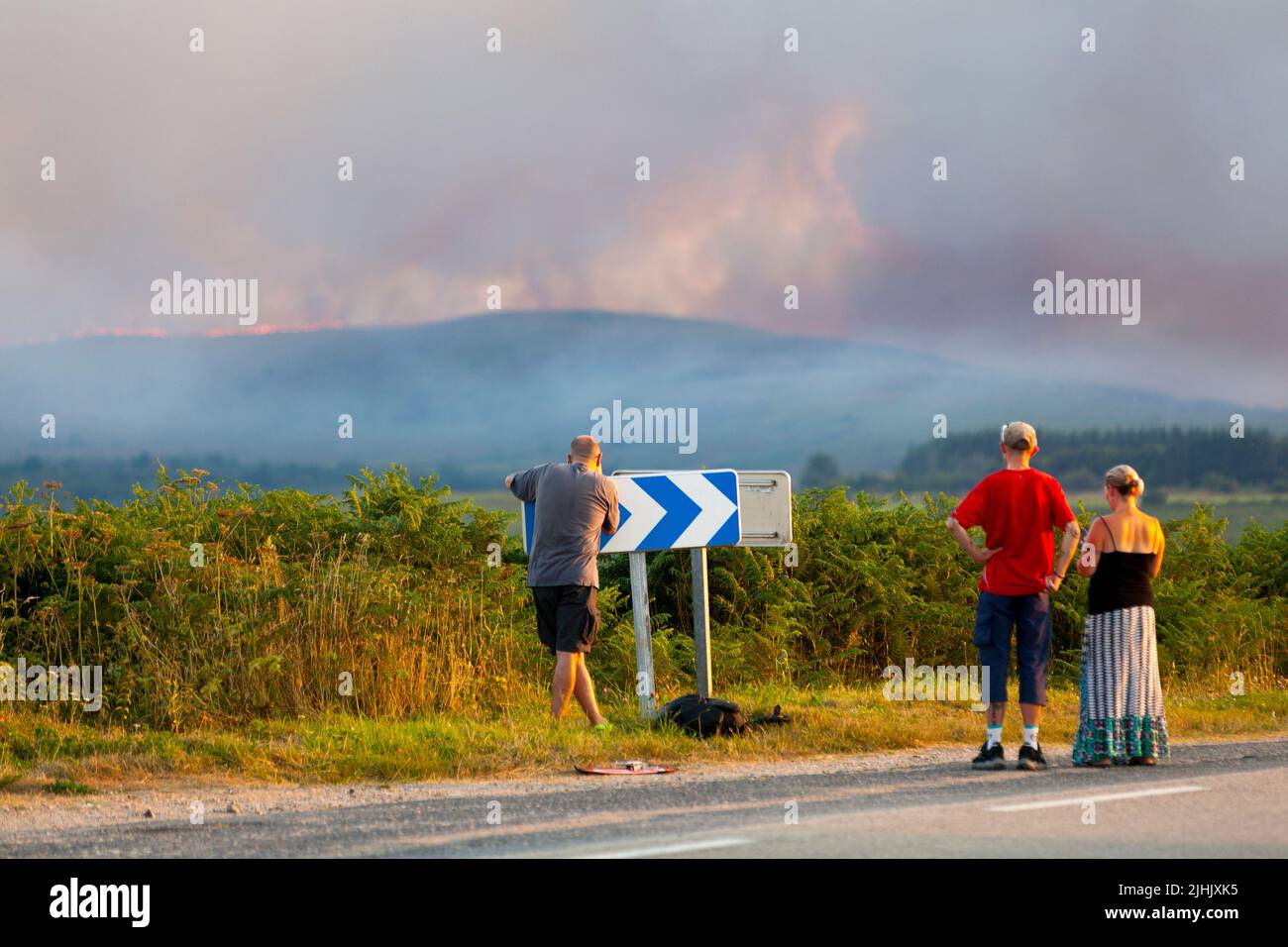 Menschen beobachten von der Straße nach Brasteils aus der Ferne das Feuer in den Monts d'Arrée oberhalb von Brasteils während des Feuers vom 18. Juli 2022. Stockfoto