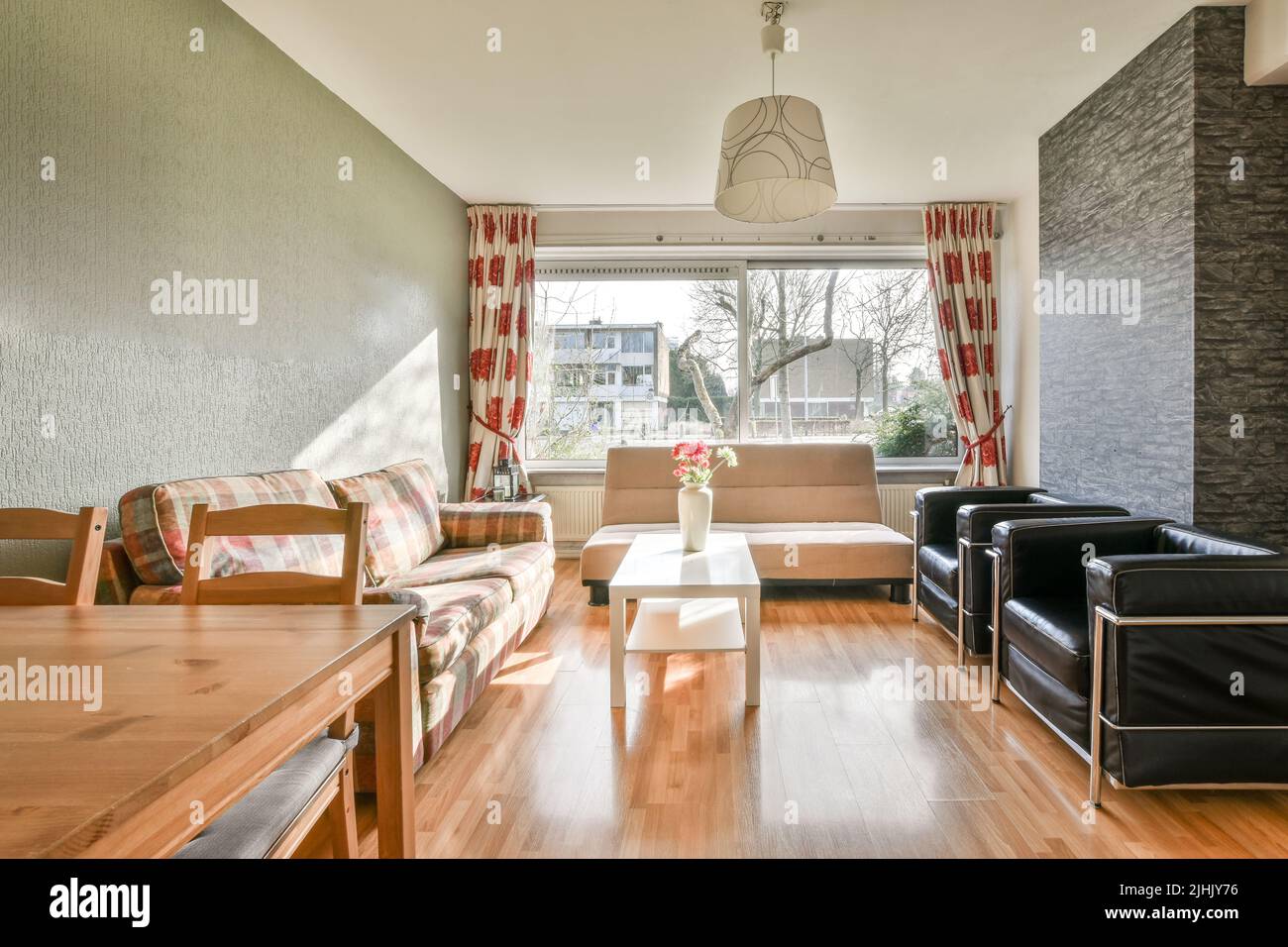 Einfache, teure Innenausstattung des Wohnzimmers mit Sofa in der Nähe eines großen Fensters Stockfoto