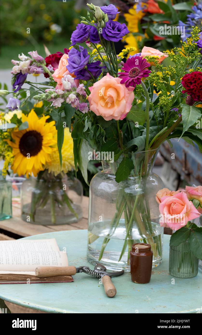 Schneiden Sie Blumen in Glasvasen auf einem Gartentisch. VEREINIGTES KÖNIGREICH Stockfoto