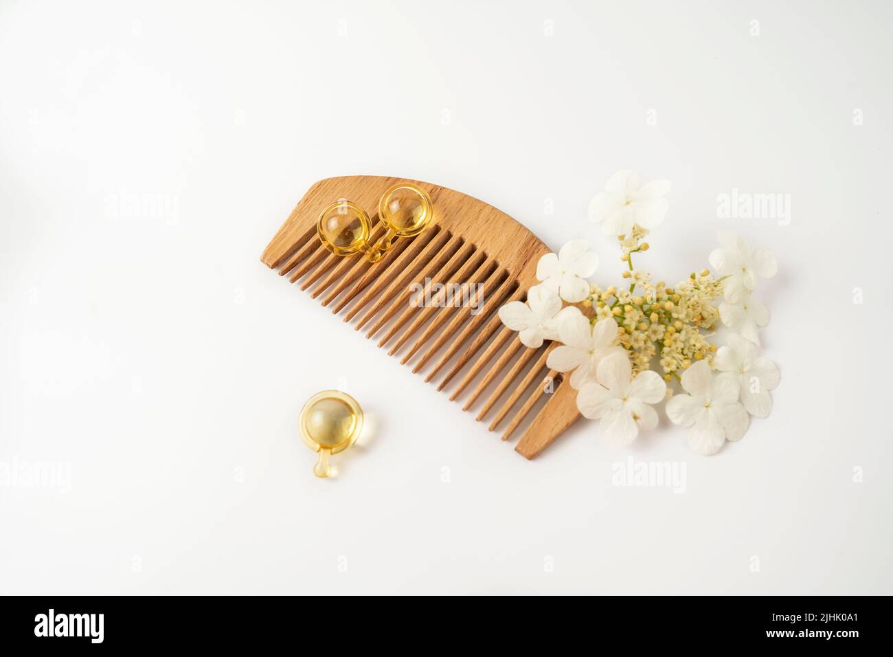 Naturölvitamine goldene Kapseln für Haare, die auf einem Holzkamm liegen Stockfoto