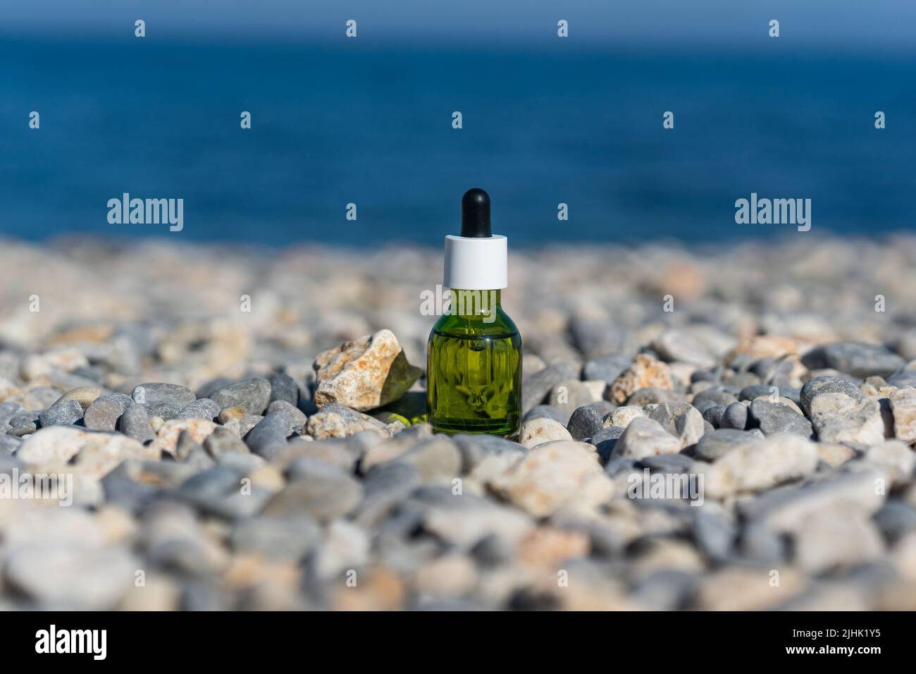 Ein natürliches ätherisches Öl oder Serum, das auf den Steinen am Meer steht Stockfoto