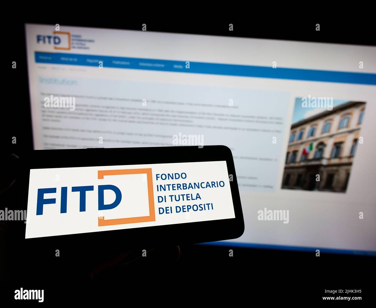 Person, die das Smartphone mit dem Logo von Fondo Interbancario di Tutela dei Depositi (FITD) auf dem Bildschirm vor der Website hält. Konzentrieren Sie sich auf die Telefonanzeige. Stockfoto