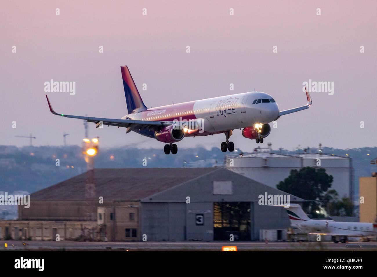 Wizz Air Airbus A321-231 (REG: HA-LXV), der nach der Start- und Landebahn 13 bei Sonnenuntergang wieder aufgeht. Stockfoto