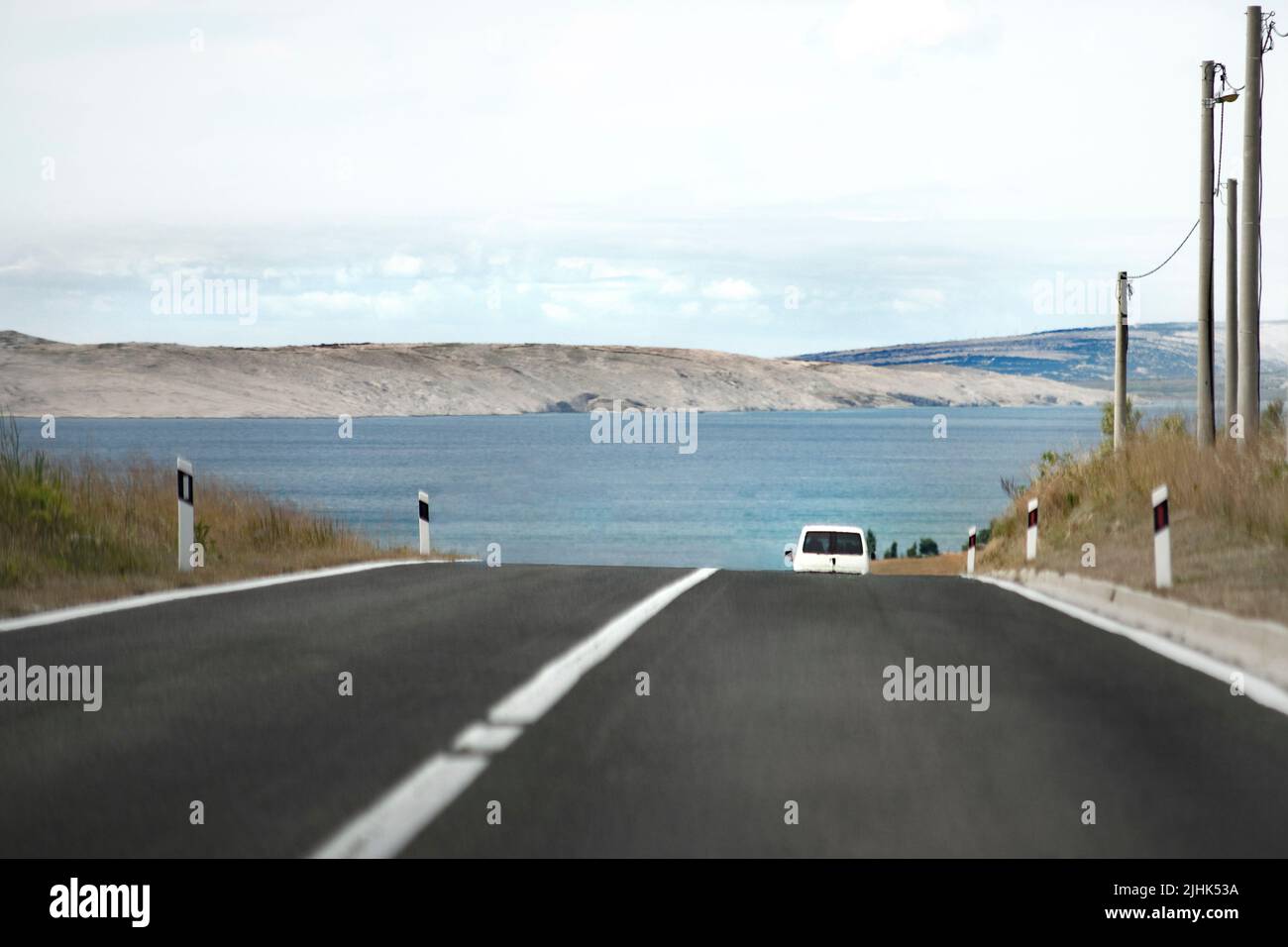 Konzept von Auto, Camper Straße reisen. Weißes Auto kaum sichtbar und verschwindet unter der Straße und geht in die Nähe des Meeres. Stockfoto