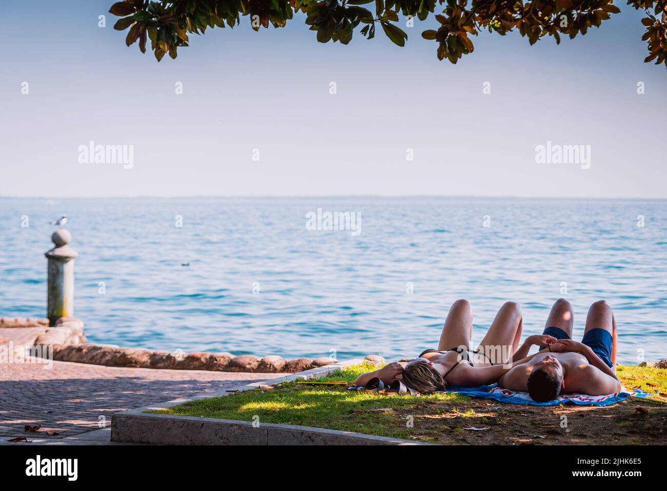 Paar sonnenbaden. Garda Promenade. Garda ist eine Stadt und Gemeinde am Ufer des Gardasees. Garda, Provinz Verona, Venetien, Italien, Europa Stockfoto