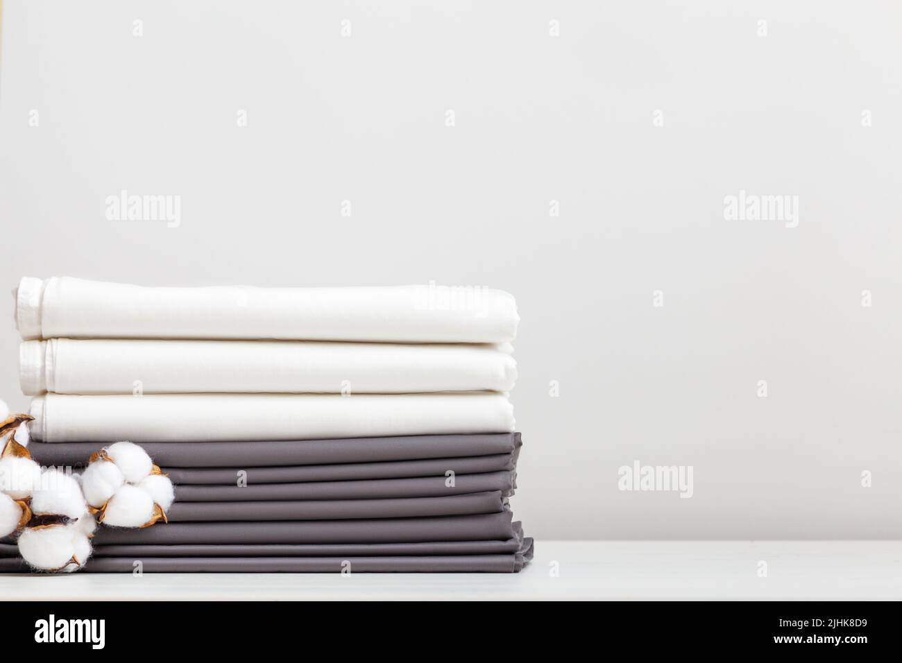 Graue und weiße Bettwäsche, Baumwollzweiglaken auf dem Tisch Stockfoto