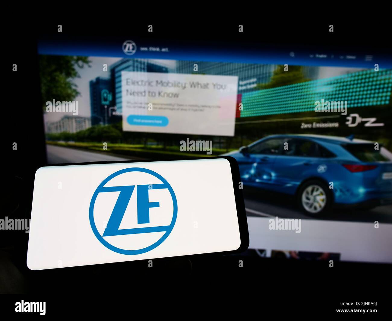 Person, die Mobiltelefon mit Logo des Automobilunternehmens ZF Friedrichshafen AG auf dem Bildschirm vor der Business-Webseite hält. Konzentrieren Sie sich auf die Telefonanzeige. Stockfoto