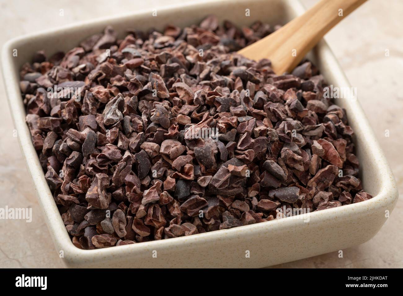 Kakaobohnen, getrocknete, zerkleinerte und fermentierte Kakaobohnen, in einer Keramikschale aus nächster Nähe Stockfoto