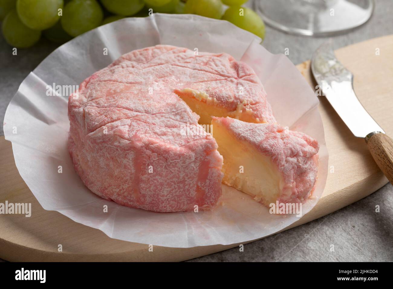Le Rose, weicher französischer Käse mit Kuhmilch und verfeinert mit Rosé-Champagner und einem Stück Nahaufnahme auf einem Schneidebrett Stockfoto