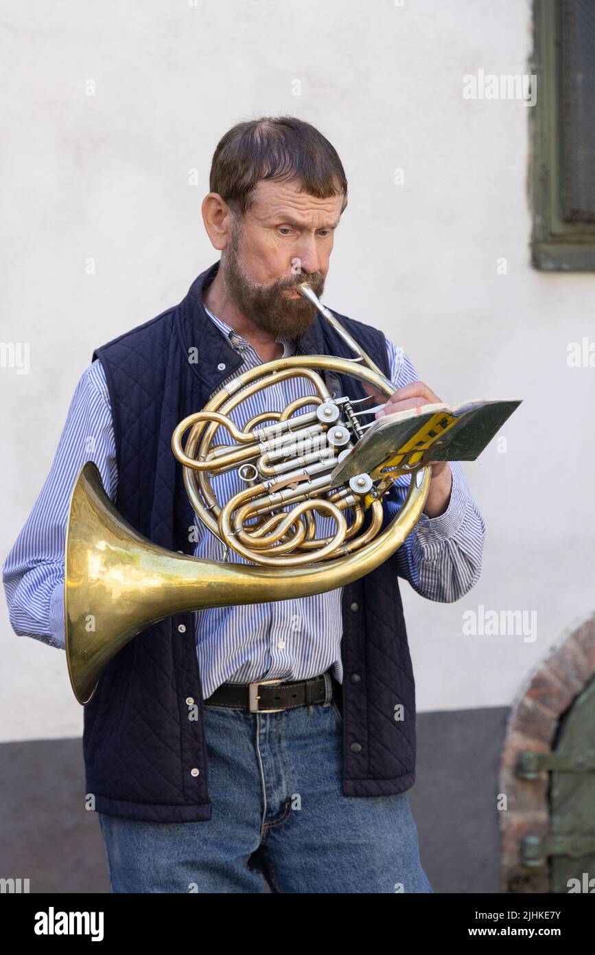 Die Altstadt von Riga ist ein Straßenmusiker, ein Mann im mittleren Alter von 50s Jahren, der auf dem französischen Horn spielt, die Altstadt von Riga, Riga Lettland Europa - Beispiel für den Lebensstil in Riga Stockfoto