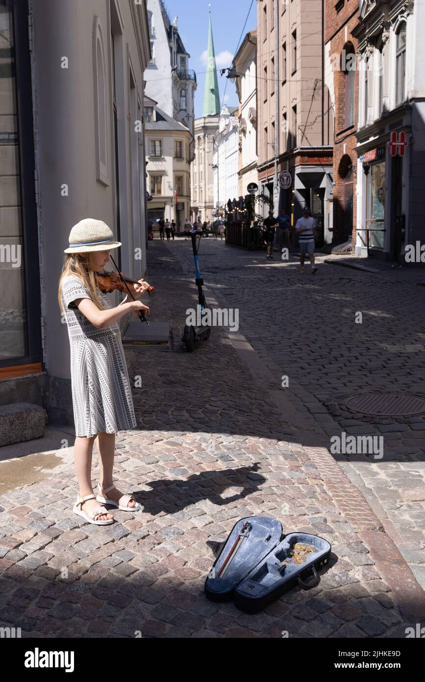 Kinder-Straßenunterhalter Riga; ein junges Mädchen im Alter von 10 Jahren, das auf der Geige Musik spielt, um Geld zu sammeln, Altstadt von Riga, Riga, Lettland, Europa Stockfoto