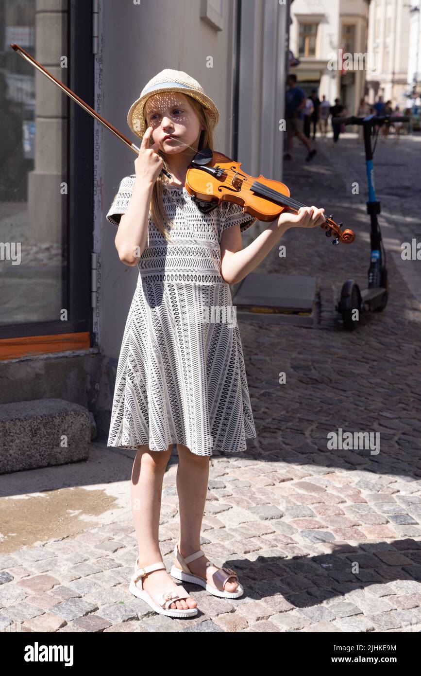 Kinder-Straßenunterhalter Riga; ein junges Mädchen im Alter von 10 Jahren, das auf der Geige Musik spielt, um Geld zu sammeln, Altstadt von Riga, Riga, Lettland, Europa Stockfoto