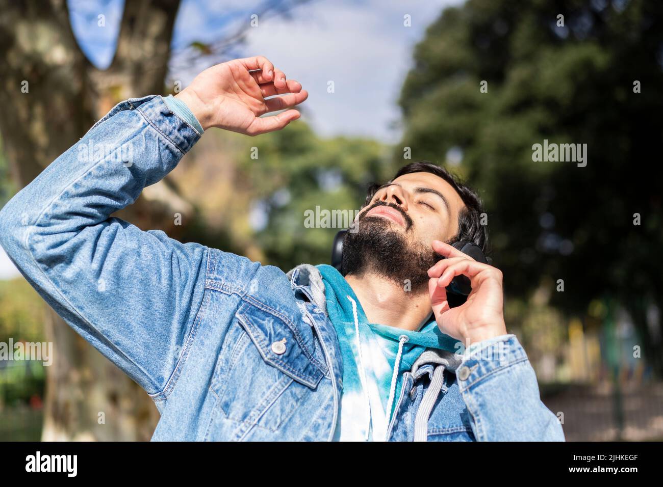 Junger latein hört Musik im Freien mit Kopfhörern. Ausdruck von Glück, gewinnende Haltung. Stockfoto