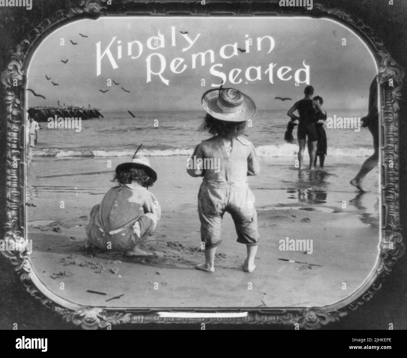 Bitte sitzen bleiben - Foto zeigt Kinder am Strand. Positiver Papierdruck von Laternendia, der in Filmtheatern als Ankündigung verwendet wurde, um 1912 Stockfoto