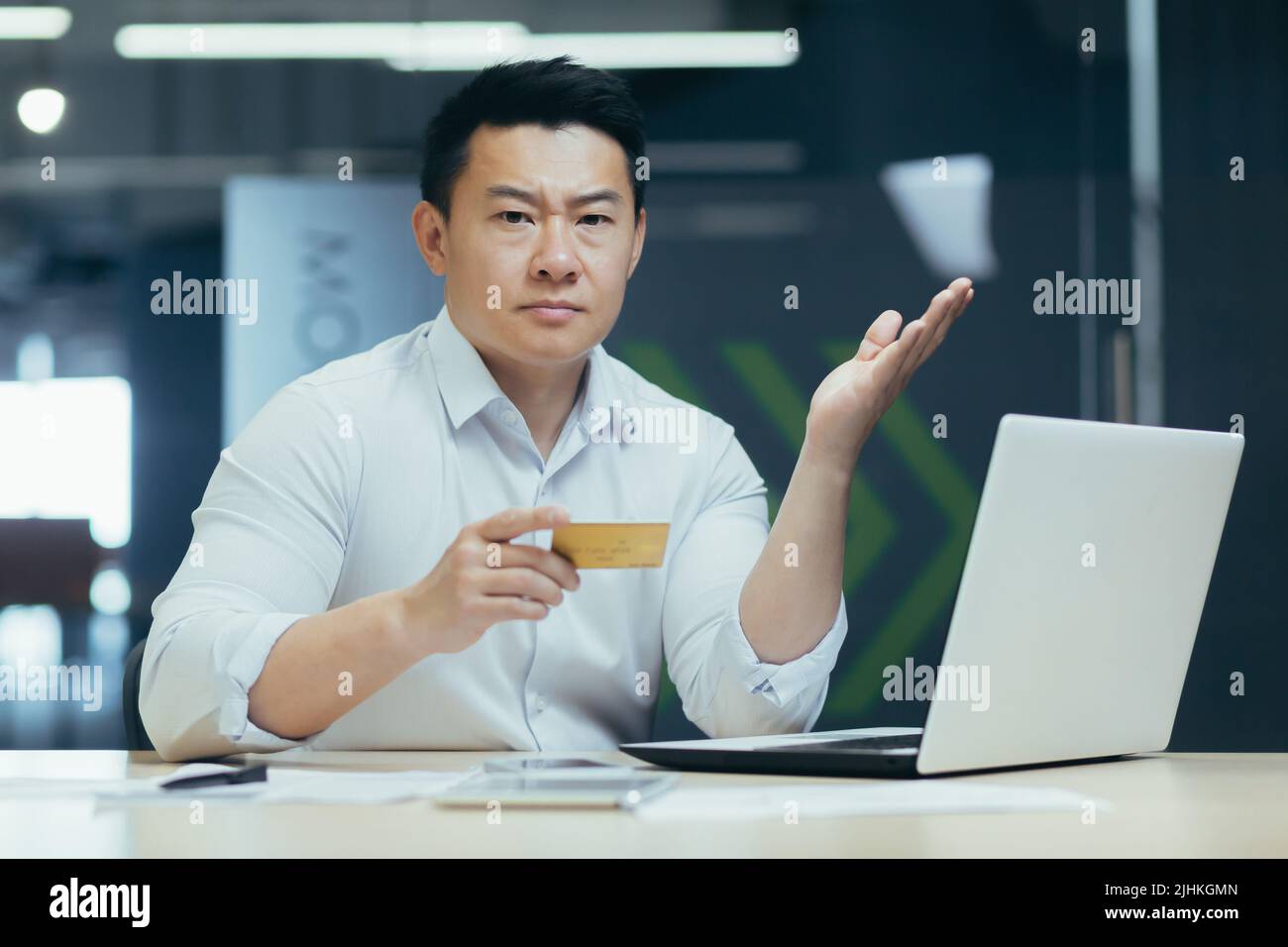 Porträt eines frustrierten und verärgerten Geschäftsmannes, eines Mannes, der im Büro arbeitet, die Kreditkarte hält und die Kamera anschaut, besorgt über das Kreditlimit und verärgert Stockfoto