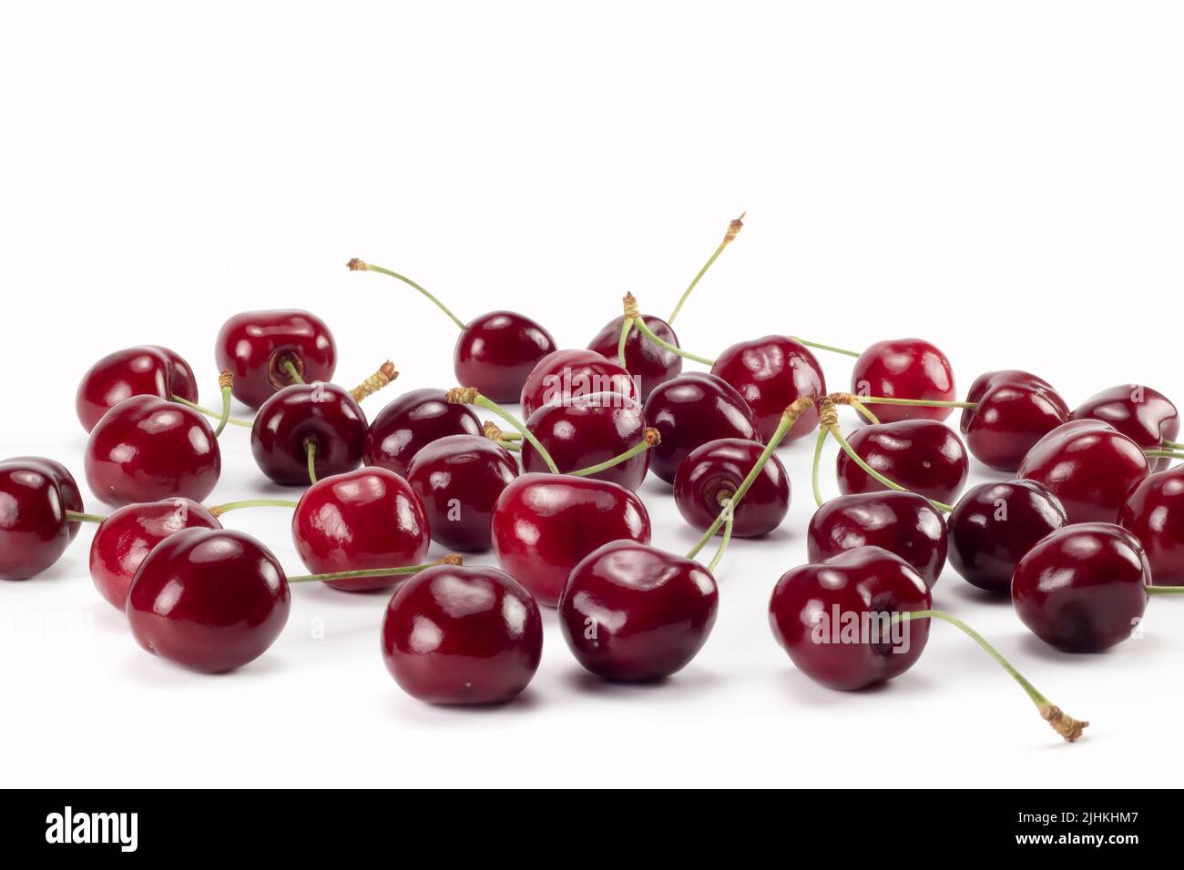 Viele reife Kirschen auf hellem Hintergrund verstreut. Nahaufnahme. Stockfoto