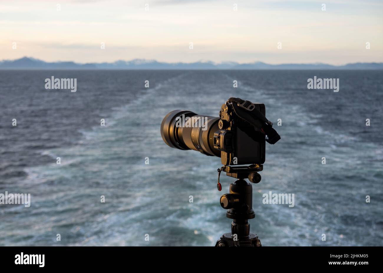 Professionelle dslr auf Stativ auf der Rückseite eines von der Küste Alaskas abfahrenden Kreuzschiffs, das aufwacht Stockfoto
