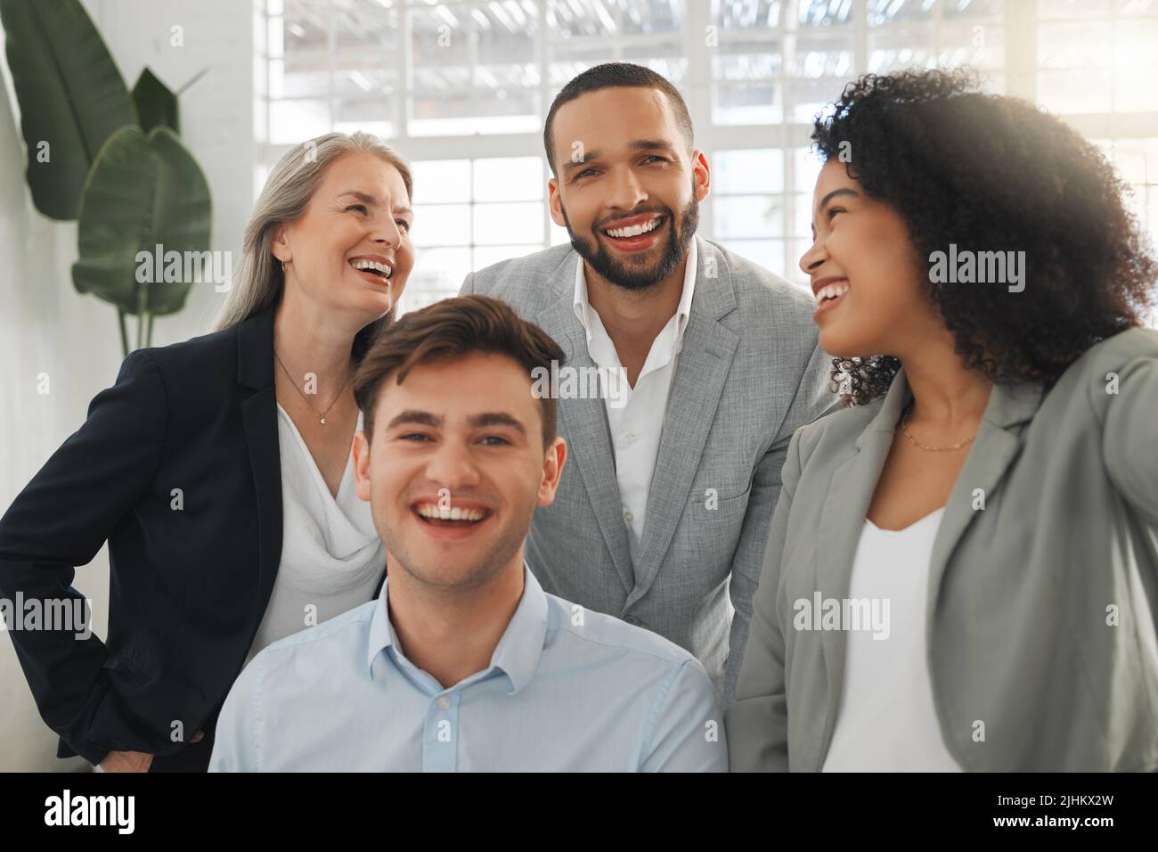 Eine Gruppe von vier fröhlichen, vielfältigen und positiven Geschäftsleuten, die zusammen ein Selfie bei der Arbeit machen. Glückliche hispanische Geschäftsfrau, die mit ihr ein Foto macht Stockfoto