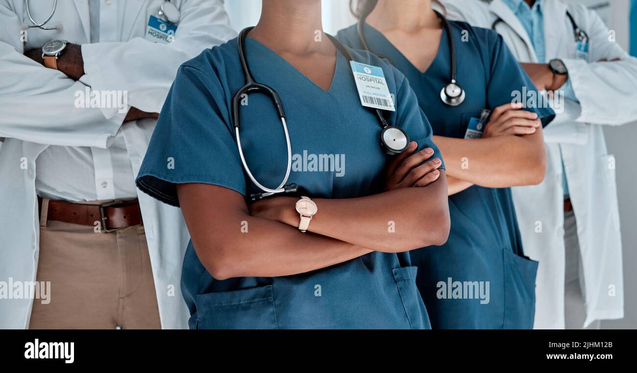 Eine Gruppe von Ärzten, die während der Arbeit in einem Krankenhaus mit gekreuzten Armen stehen. Fachkundige medizinische Fachkräfte, die in einer Klinik zusammenarbeiten Stockfoto