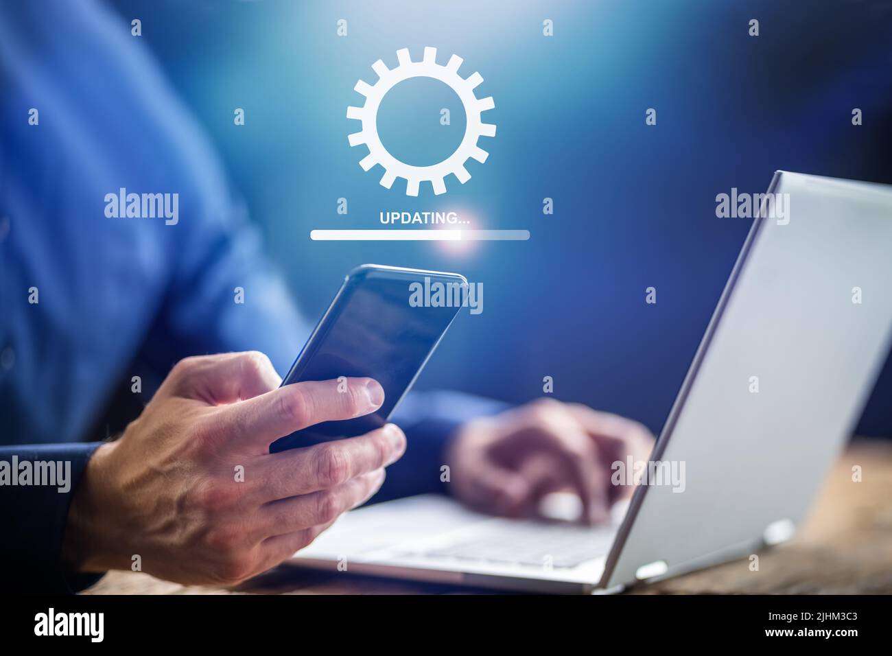 Mann, Der Software-Update Auf Mobiltelefon Und Laptop Macht Stockfoto