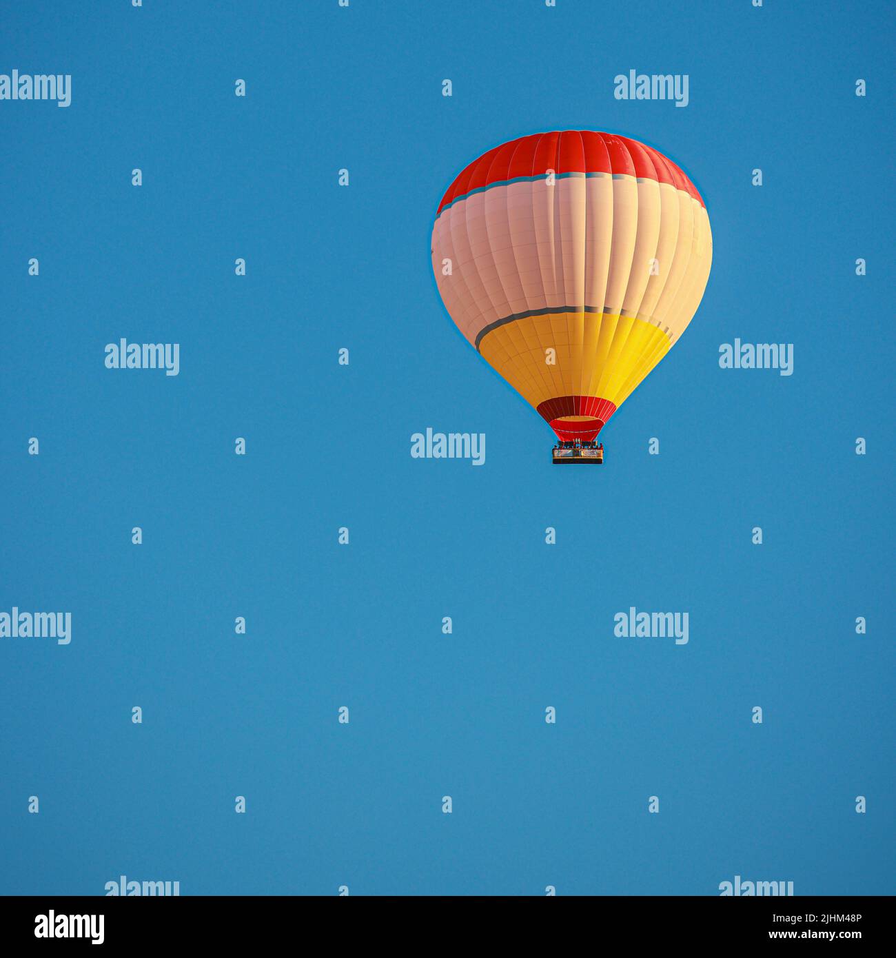 Einsamer Heißluftballon fliegt in blauem Himmel. Stockfoto