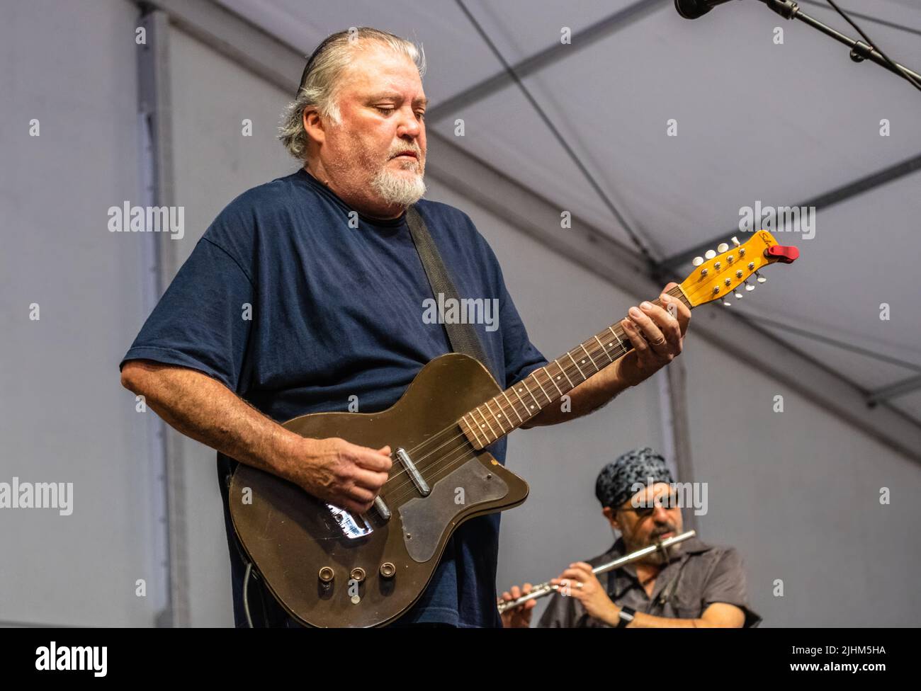 NEW ORLEANS, LA, USA - 3. MAI 2019: David Hidalgo spielt Leadgitarre auf Silvertone Electric mit Steve Berlin im Hintergrund auf Flöte für Los Lobos Stockfoto