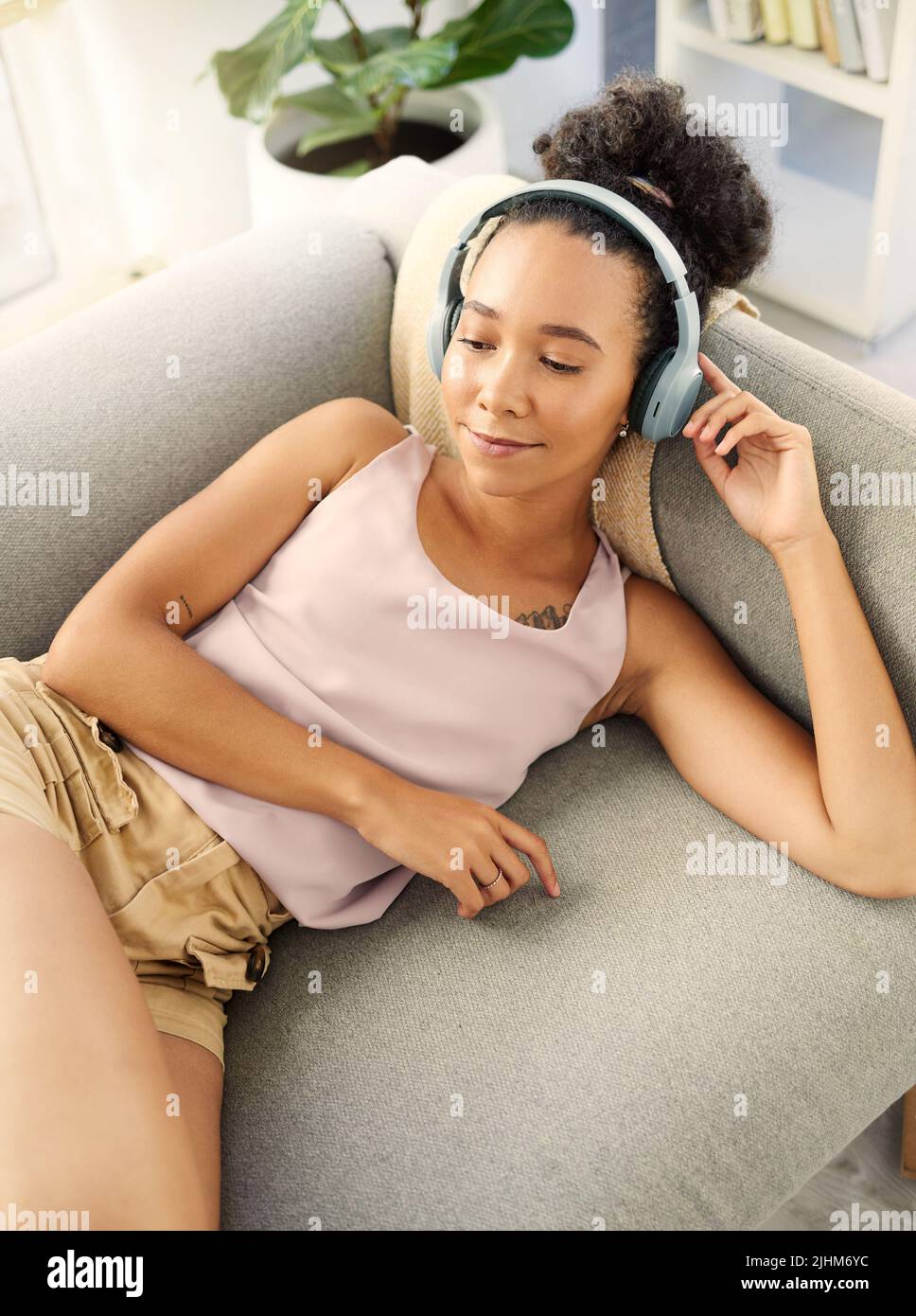 Eine junge Frau, die Musik hört, während sie sich zu Hause entspannt. Stockfoto