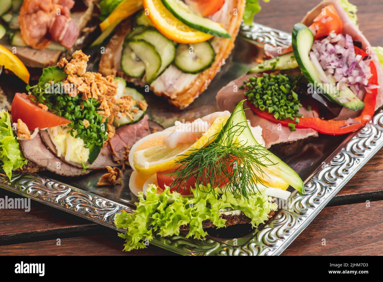 Traditionelle dänische Smørrebrød oder offene Sandwiches auf einem Teller, Roastbeef mit Remoulade, Tomaten und geriebenem Meerrettich auf dänischem Roggenbrot Stockfoto