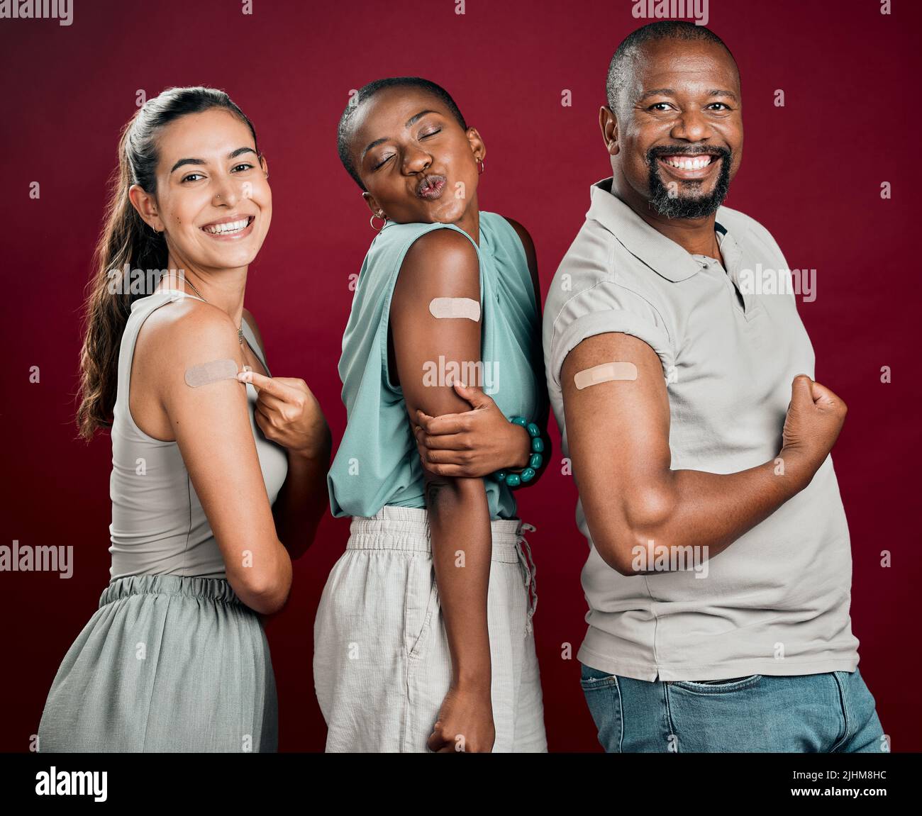 Covid geimpfte verschiedene Gruppen von Menschen, die Gips am Arm zeigten. afroamerikanischer Mann und Frau mit gemischter Frau isoliert auf rotem Studio Stockfoto