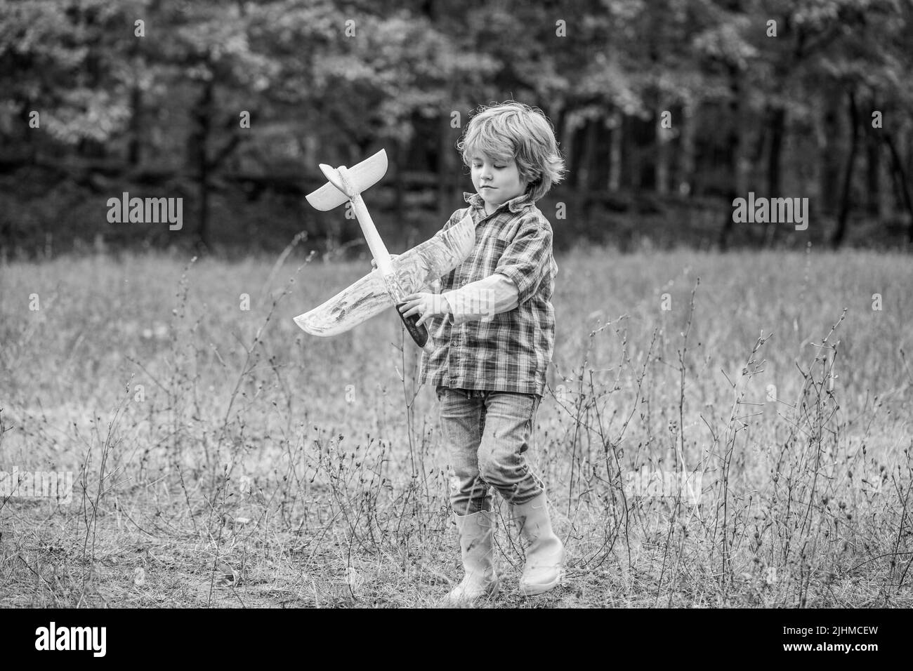 Glückliches Kind spielt im Freien. Glücklich Junge spielen Flugzeug. Kleiner Junge mit Flugzeug. Kleines Kind träumt davon, Pilot zu sein. Kind spielt mit Spielzeug Flugzeug Stockfoto