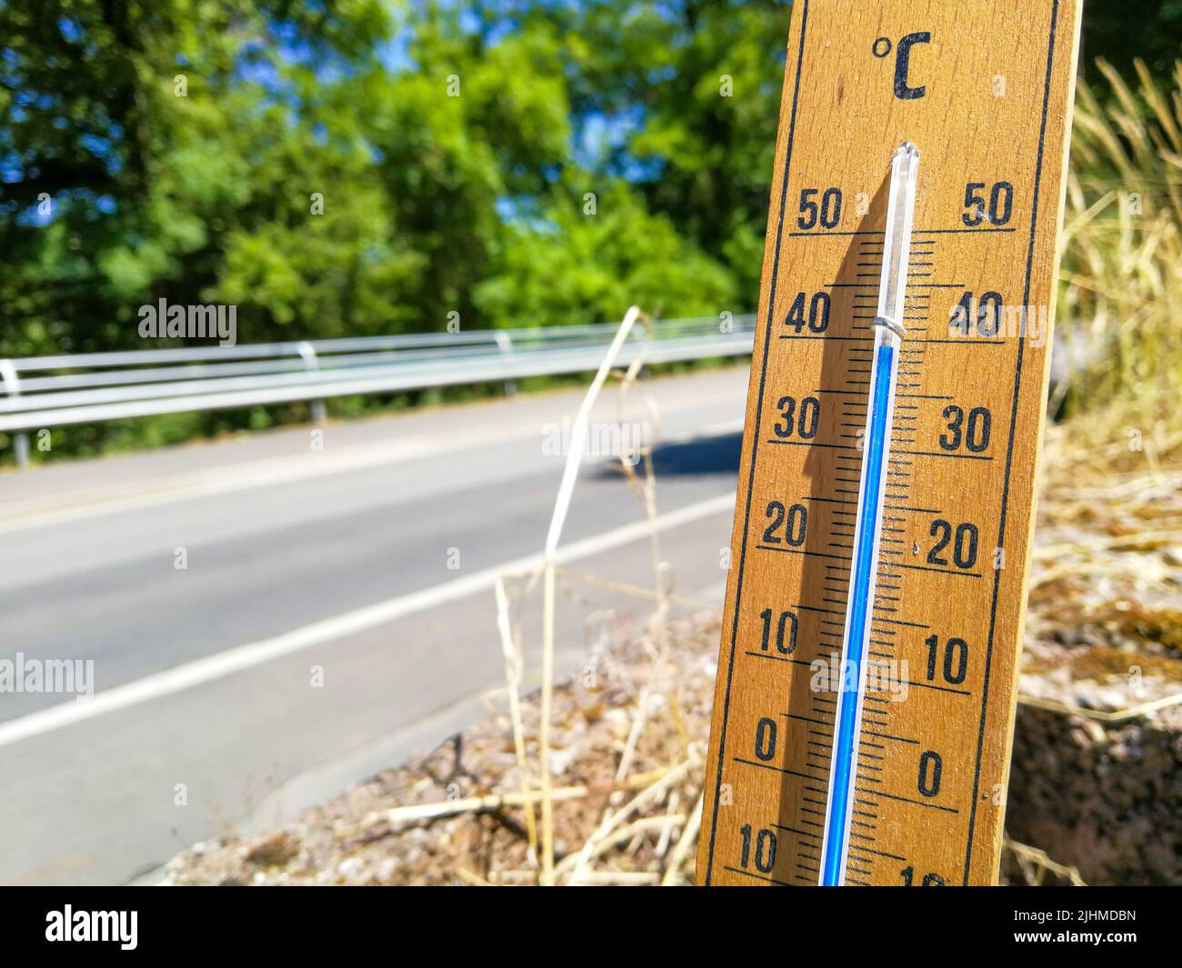 Detail des Thermometers zeigt hohe Temperaturen von über 35 im Sommer gegen Bäume und wolkenlosen Himmel mit Fokus auf Thermometer Stockfoto