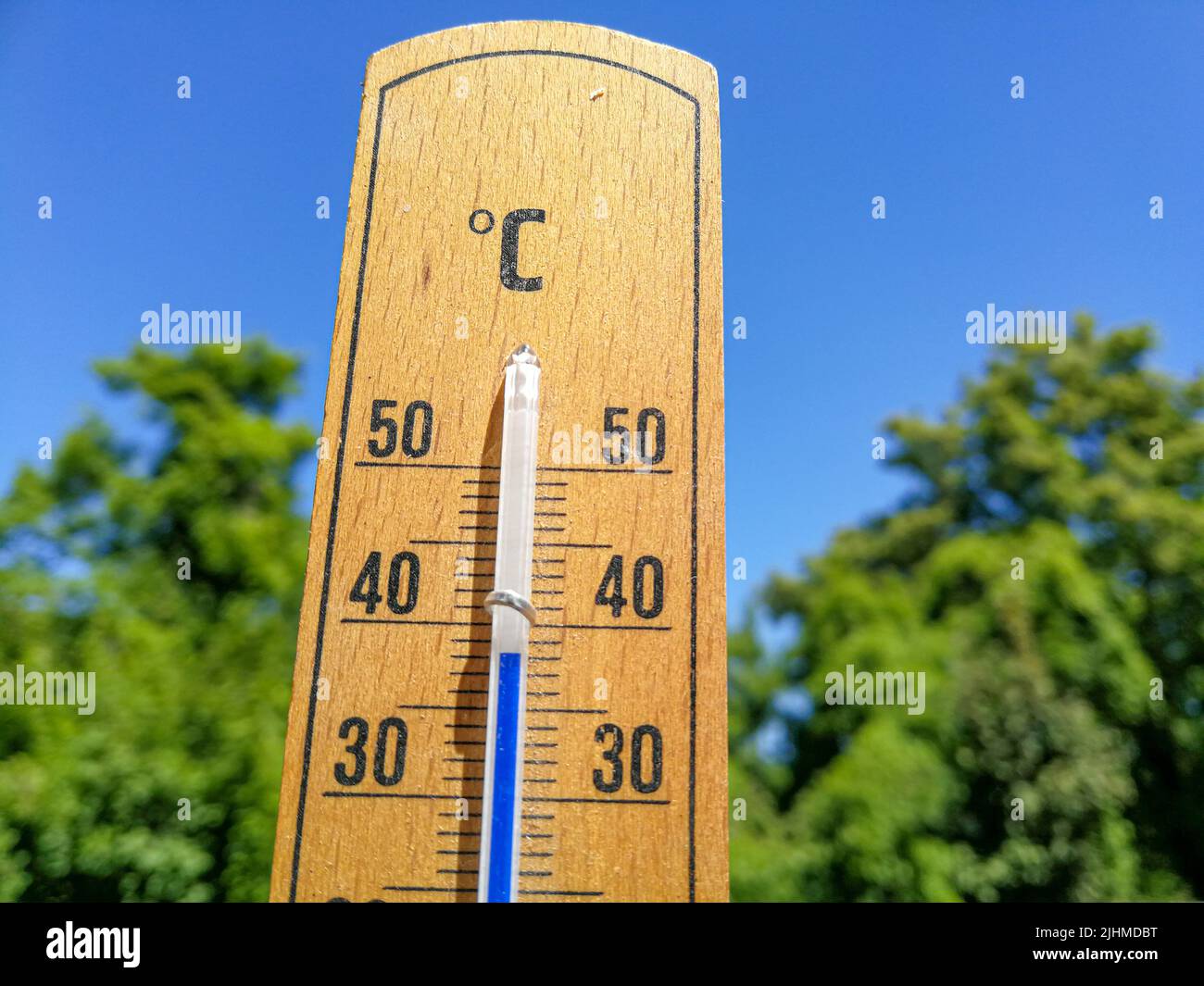 Detail des Thermometers zeigt hohe Temperaturen von über 35 im Sommer gegen Bäume und wolkenlosen Himmel mit Fokus auf Thermometer Stockfoto