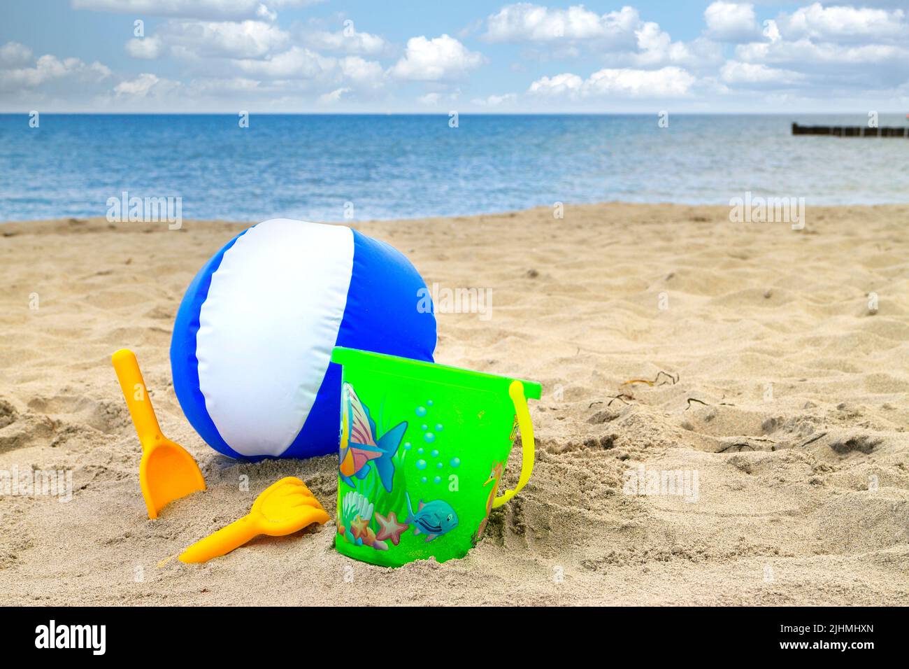 Ball und Spielzeug am sonnigen Sommerstrand mit Meer und Himmel im Hintergrund Stockfoto
