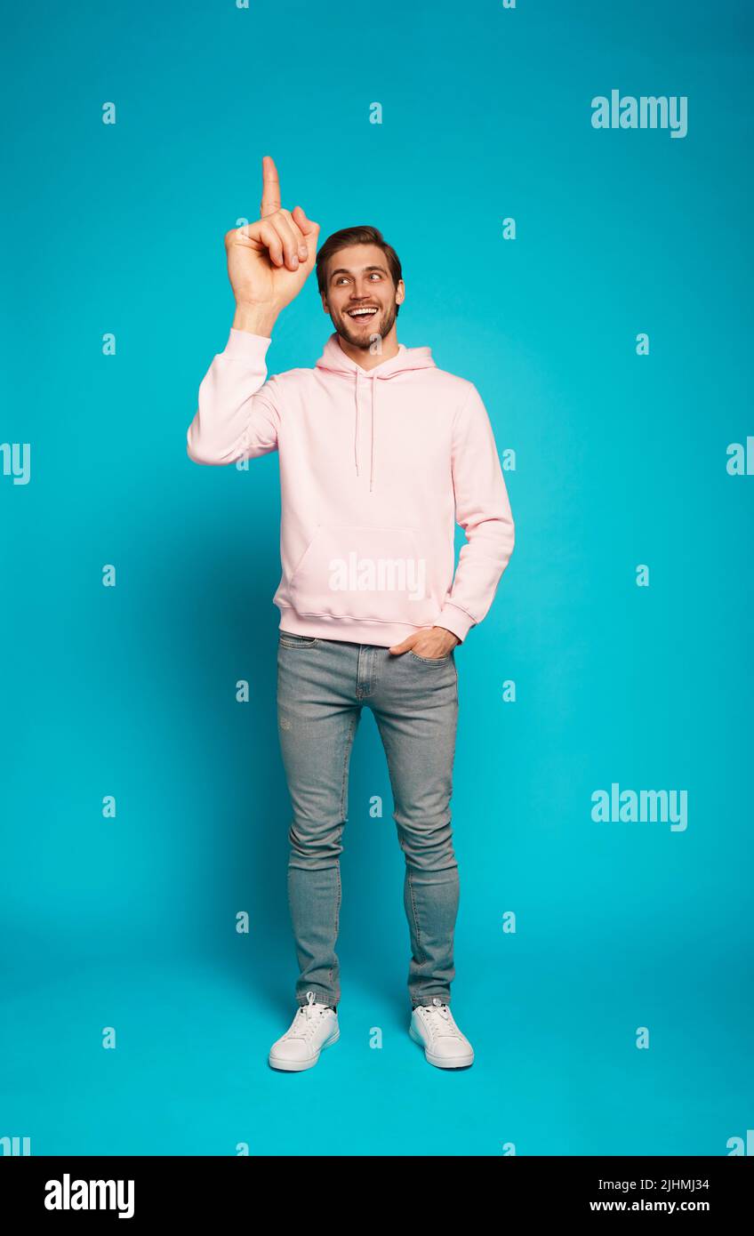 Foto in voller Größe von einem aufgeregt glücklichen Mann, der mit dem Finger auf den Copyspace zeigt, isoliert auf einem hellblauen Hintergrund. Stockfoto