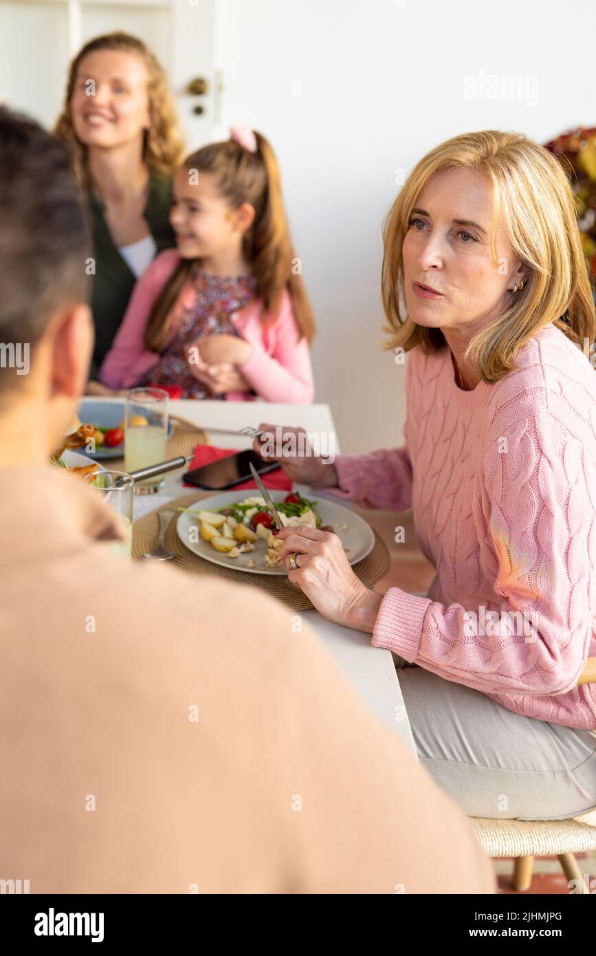 Vertikales Bild einer glücklichen, erweiterten kaukasischen Familie, die zusammen ein Abendessen isst Stockfoto