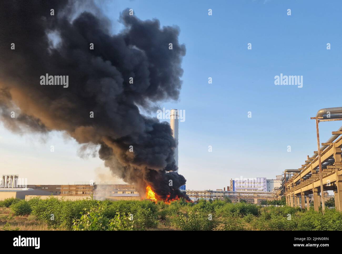 Premnitz, Deutschland. 19.. Juli 2022. Eine Wolke aus schwarzem Rauch erhebt sich über einer Chemiefabrik. In einem Lager eines Chemiefaserherstellers im Bezirk Havelland brach am Dienstagabend ein weithin sichtbares Feuer aus. Es gab eine starke Rauchentwicklung, sagte ein Feuerwehrsprecher am Abend, in der Halle wahrscheinlich Kunststoff und Holz gelagert. Die Halle gehört einem Polyesterfaserhersteller. Quelle: Cevin Dettlaff/dpa-Zentralbild/dpa/Alamy Live News Stockfoto