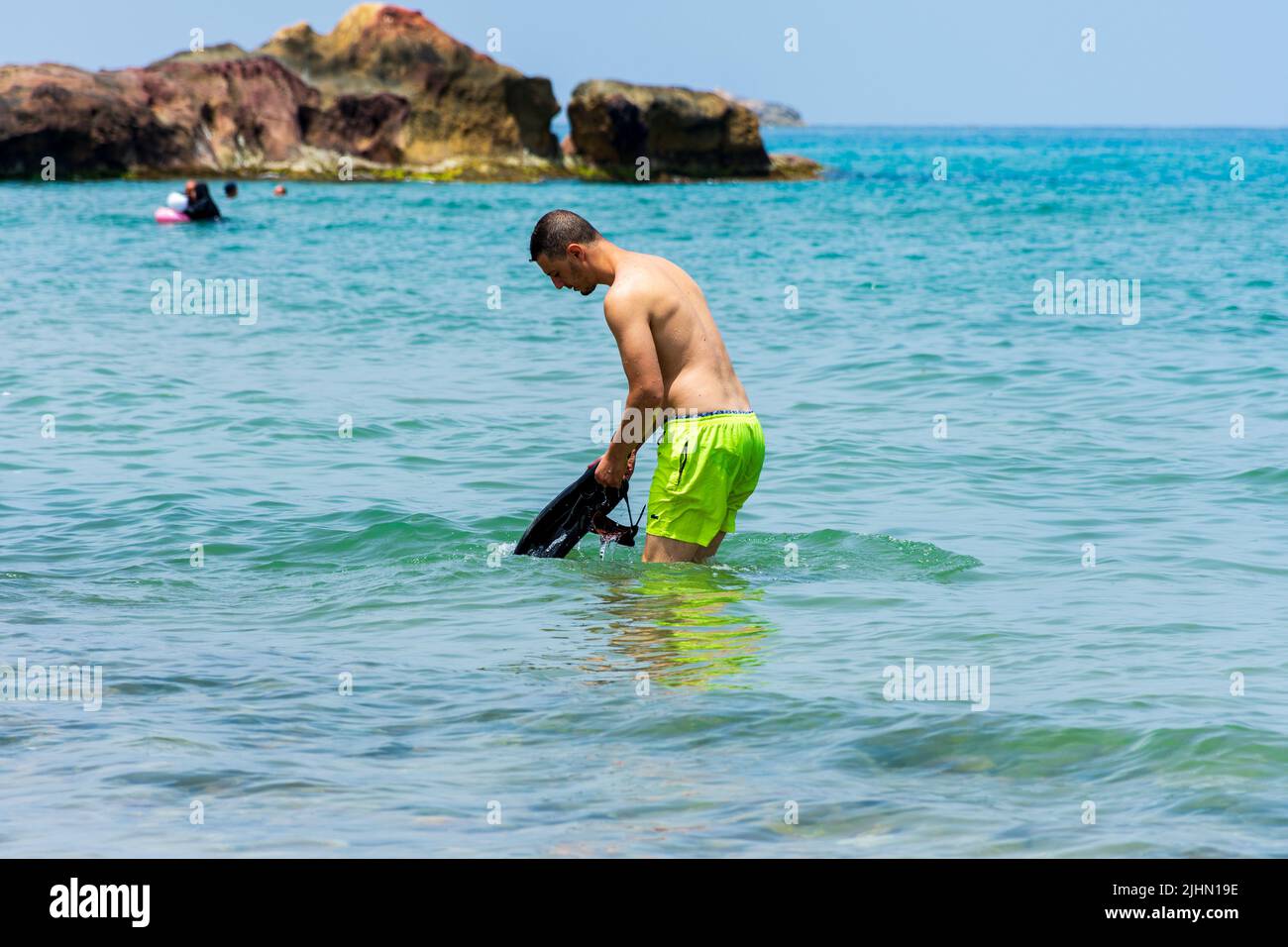 Junger Araber, der in der Nähe des Strandes im Mittelmeer steht. Konzept für Sommerferien. Stockfoto